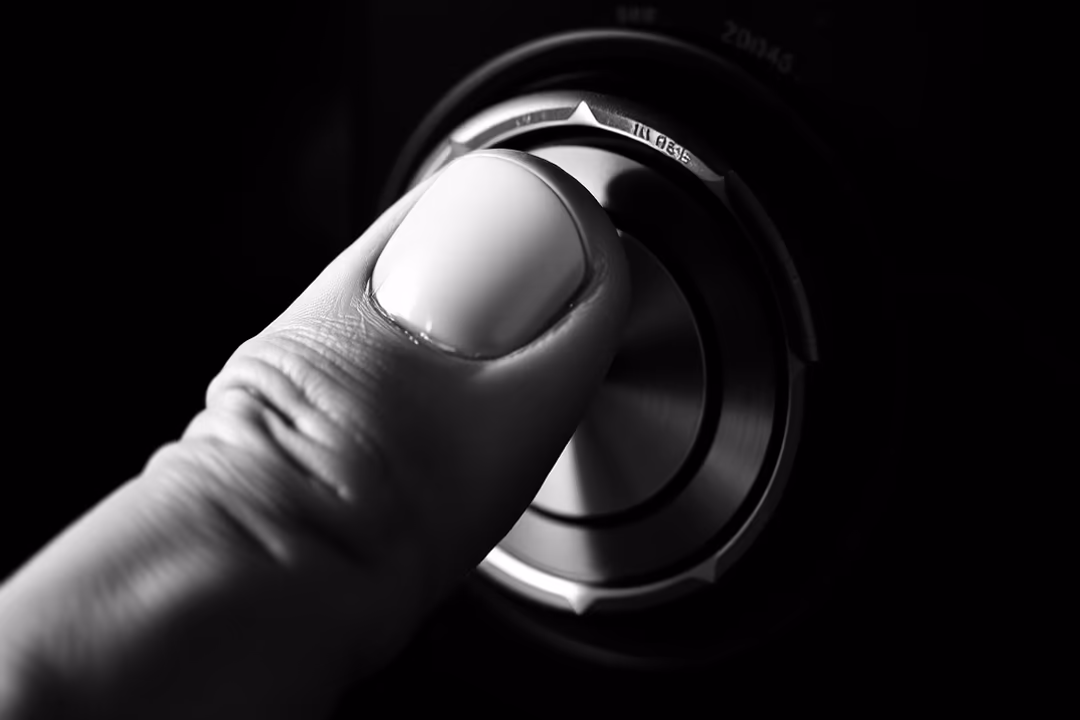 A close-up of a finger pressing a metallic knob on a device, set against a dark background.